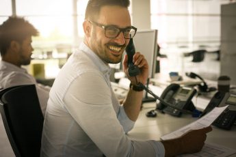 Caucasian business man having conversation on Landline phone. Business man in office. Looking at camera.